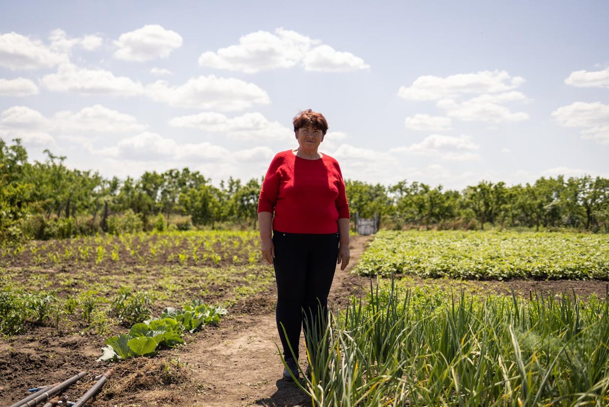 A woman in a red shirt stands in her field of crops.