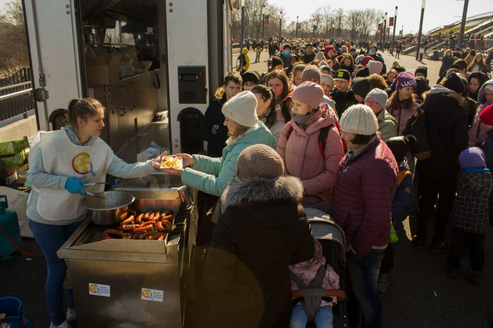 Families impacted by the war in Ukraine line up to receive a meal from a World Central Kitchen team member.
