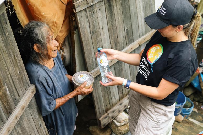 Margarita stands in front of her home receiving a meal from a WCK team member.