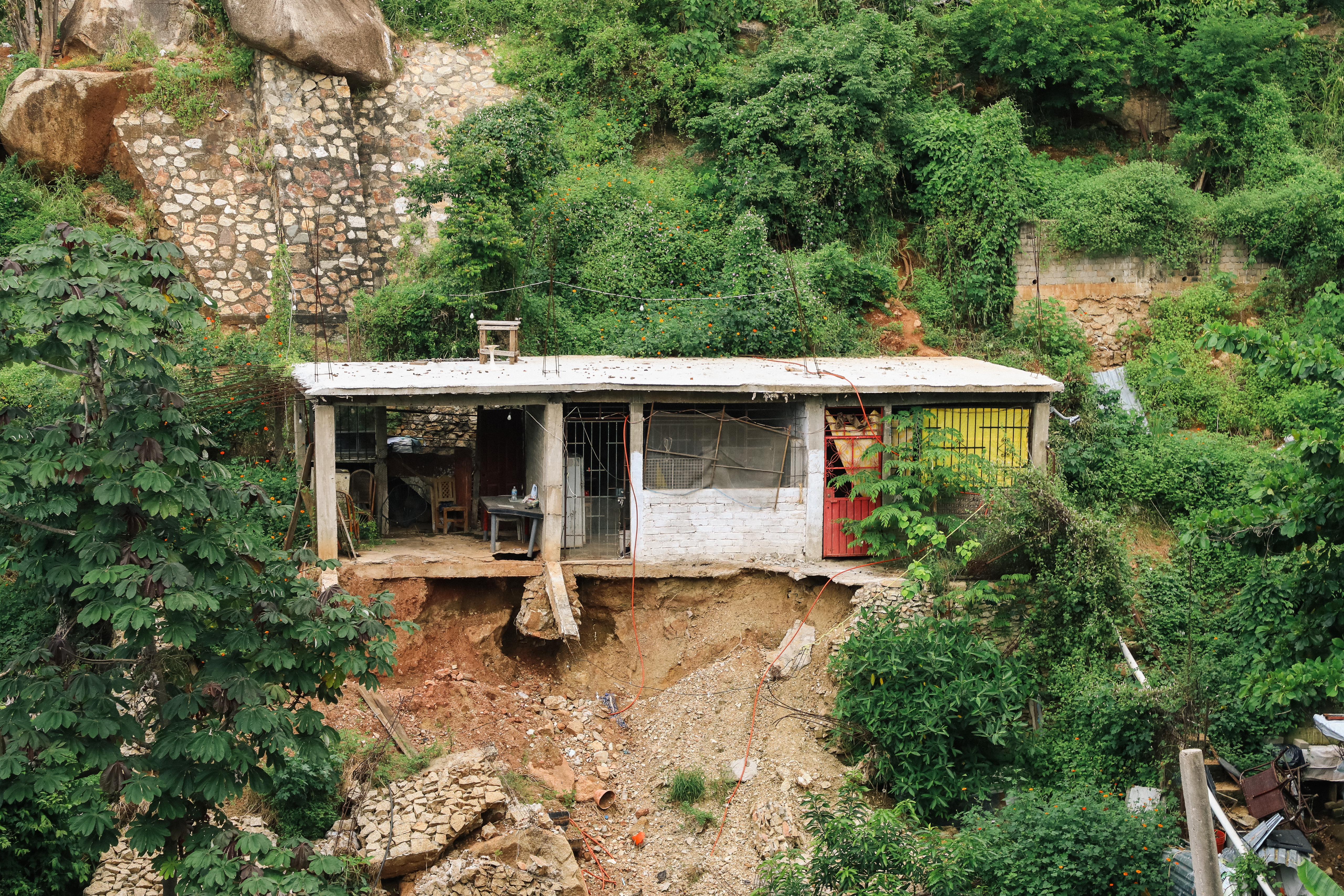 MArgarita's home on a hillside with damaged walls from Hurricane Otis.